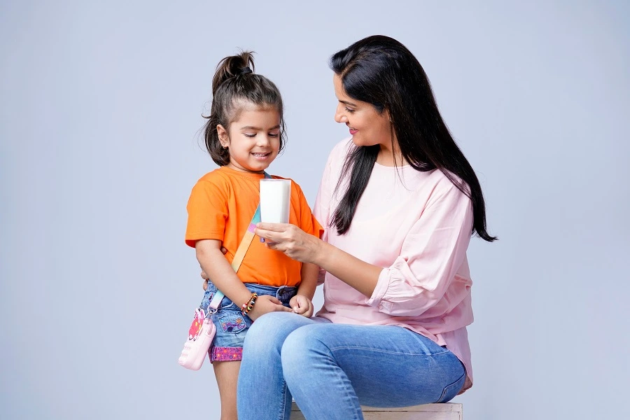 Indian mother with a glass of milk with young daughter